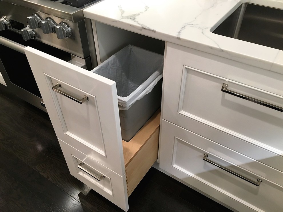 Inspiration for a mid-sized timeless l-shaped dark wood floor eat-in kitchen remodel in Philadelphia with a farmhouse sink, shaker cabinets, white cabinets, marble countertops, white backsplash, stone slab backsplash, stainless steel appliances and an island