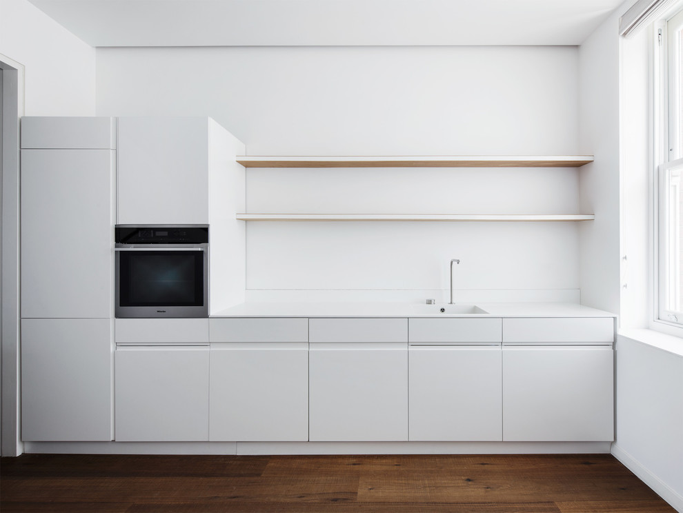 Foto de cocina lineal contemporánea con armarios con paneles lisos, puertas de armario blancas, suelo de madera oscura y una isla