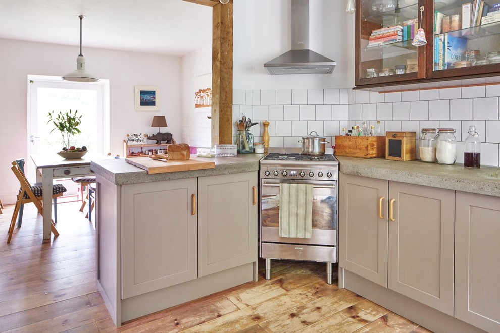 Design ideas for a bohemian kitchen/diner in Devon with a belfast sink, shaker cabinets, brown cabinets, concrete worktops, metro tiled splashback and light hardwood flooring.