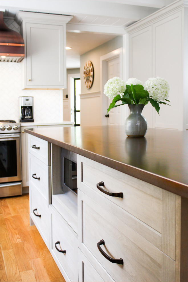 Exempel på ett mellanstort lantligt brun brunt l-kök, med luckor med infälld panel, skåp i ljust trä, bänkskiva i zink, vitt stänkskydd, stänkskydd i marmor, rostfria vitvaror, mellanmörkt trägolv, en köksö och brunt golv