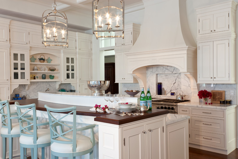 Inredning av ett lantligt stort kök med öppen planlösning, med en rustik diskho, luckor med profilerade fronter, vita skåp, marmorbänkskiva, vitt stänkskydd, stänkskydd i marmor, rostfria vitvaror, mellanmörkt trägolv och en köksö