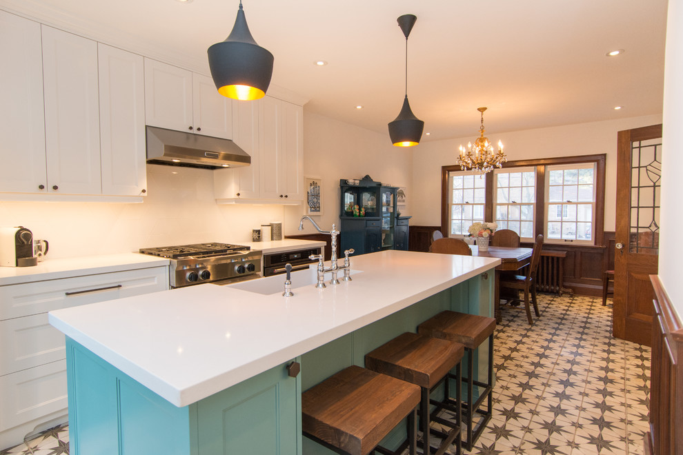 Inspiration for a mid-sized transitional u-shaped ceramic tile eat-in kitchen remodel in Toronto with a farmhouse sink, flat-panel cabinets, white cabinets, quartz countertops, white backsplash, glass tile backsplash, stainless steel appliances and an island