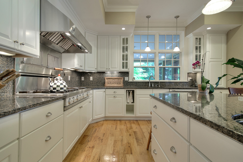 Large traditional u-shaped kitchen/diner in Portland Maine with an integrated sink, raised-panel cabinets, yellow cabinets, granite worktops, grey splashback, stone tiled splashback, stainless steel appliances, slate flooring and an island.