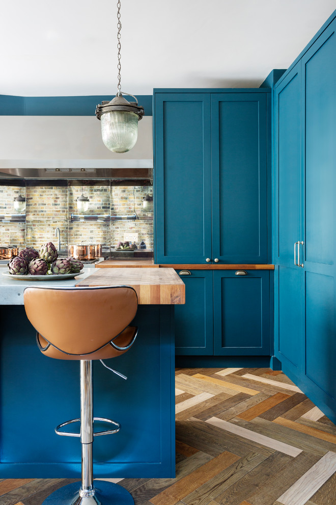 ロンドンにある高級な中くらいなエクレクティックスタイルのおしゃれなキッチン (エプロンフロントシンク、シェーカースタイル扉のキャビネット、青いキャビネット、亜鉛製カウンター、ミラータイルのキッチンパネル、シルバーの調理設備、濃色無垢フローリング、マルチカラーの床、グレーのキッチンカウンター) の写真