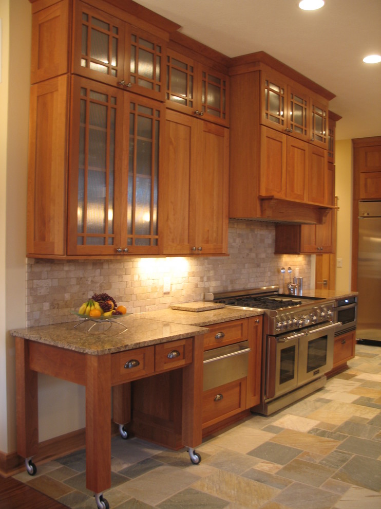 Inredning av ett amerikanskt mellanstort kök, med en undermonterad diskho, luckor med infälld panel, skåp i ljust trä, granitbänkskiva, svart stänkskydd, stänkskydd i stenkakel, rostfria vitvaror, skiffergolv och en köksö