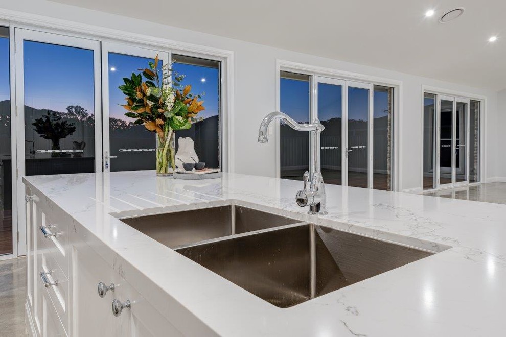 Moderne Küche mit Doppelwaschbecken, weißen Schränken, Quarzwerkstein-Arbeitsplatte und Küchengeräten aus Edelstahl in Sydney