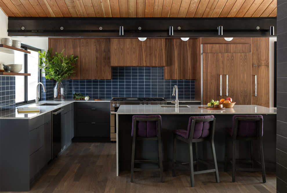 シアトルにあるミッドセンチュリースタイルのおしゃれなキッチン (アンダーカウンターシンク、フラットパネル扉のキャビネット、濃色木目調キャビネット、青いキッチンパネル、サブウェイタイルのキッチンパネル、パネルと同色の調理設備、濃色無垢フローリング、茶色い床、白いキッチンカウンター) の写真