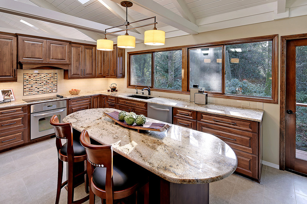 Inspiration for a large traditional u-shaped kitchen in Seattle with dark wood cabinets, metro tiled splashback, stainless steel appliances and an island.