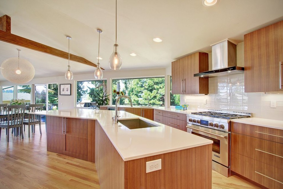 Example of a mid-sized mid-century modern l-shaped medium tone wood floor and beige floor kitchen design in Seattle with a single-bowl sink, flat-panel cabinets, brown cabinets, quartz countertops, white backsplash, ceramic backsplash, stainless steel appliances and two islands