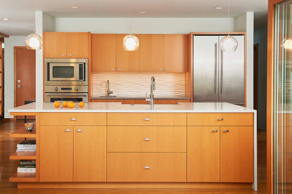 シアトルにある中くらいなミッドセンチュリースタイルのおしゃれなキッチン (フラットパネル扉のキャビネット、中間色木目調キャビネット、珪岩カウンター、白いキッチンパネル、シルバーの調理設備、無垢フローリング、茶色い床、白いキッチンカウンター) の写真
