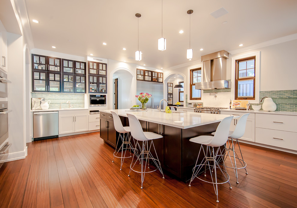 Inspiration for a transitional l-shaped medium tone wood floor kitchen remodel in Denver with shaker cabinets, white cabinets, green backsplash, stainless steel appliances and an island