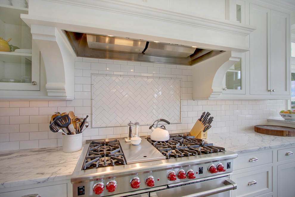 Photo of a classic kitchen in Seattle with glass-front cabinets, metro tiled splashback and stainless steel appliances.