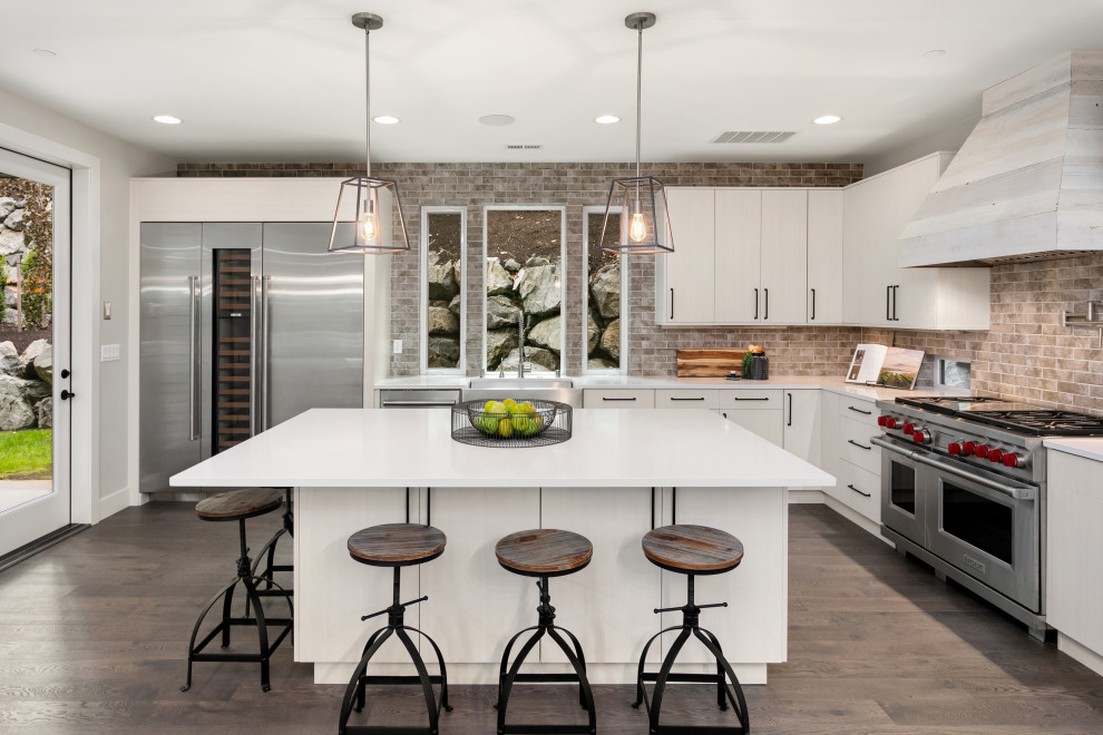 Example of a large transitional l-shaped medium tone wood floor and brown floor open concept kitchen design in Seattle with a farmhouse sink, flat-panel cabinets, white cabinets, multicolored backsplash, brick backsplash, stainless steel appliances, an island and white countertops