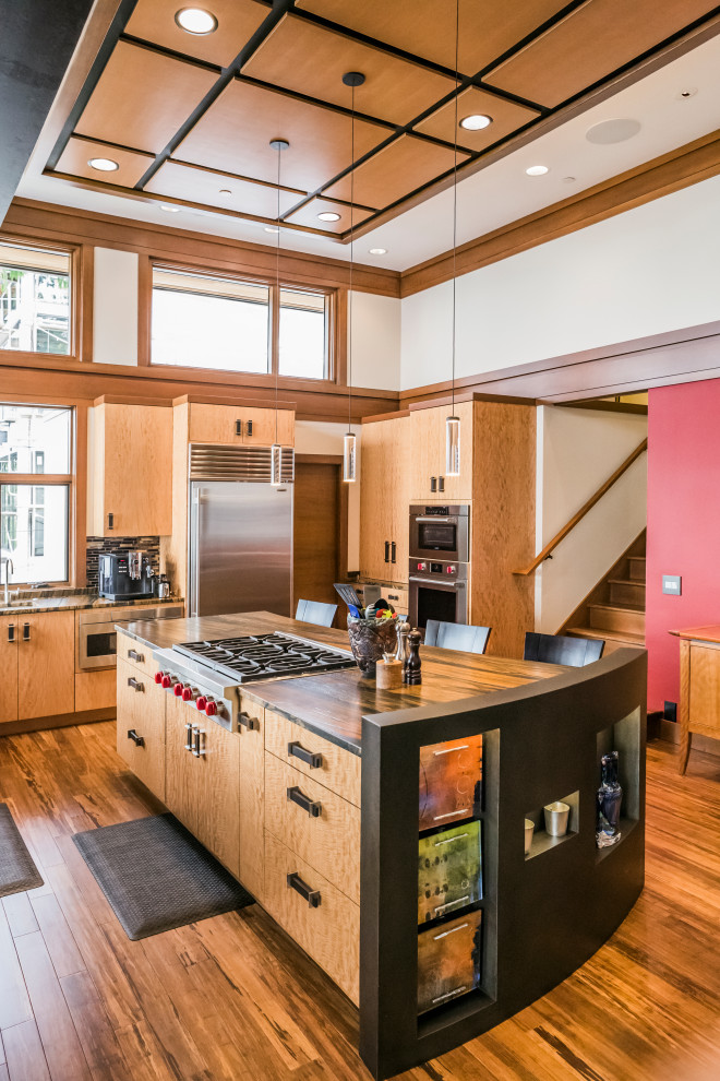 Cette image montre une cuisine design en U et bois brun avec un placard à porte plane, un électroménager en acier inoxydable, un sol en bois brun, îlot, un sol marron et un plan de travail marron.