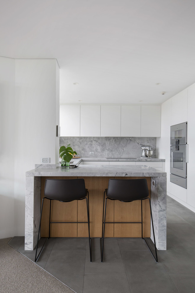 Idéer för ett avskilt, mellanstort modernt grå u-kök, med en undermonterad diskho, släta luckor, vita skåp, granitbänkskiva, grått stänkskydd, stänkskydd i sten, rostfria vitvaror, klinkergolv i keramik, en halv köksö och grått golv