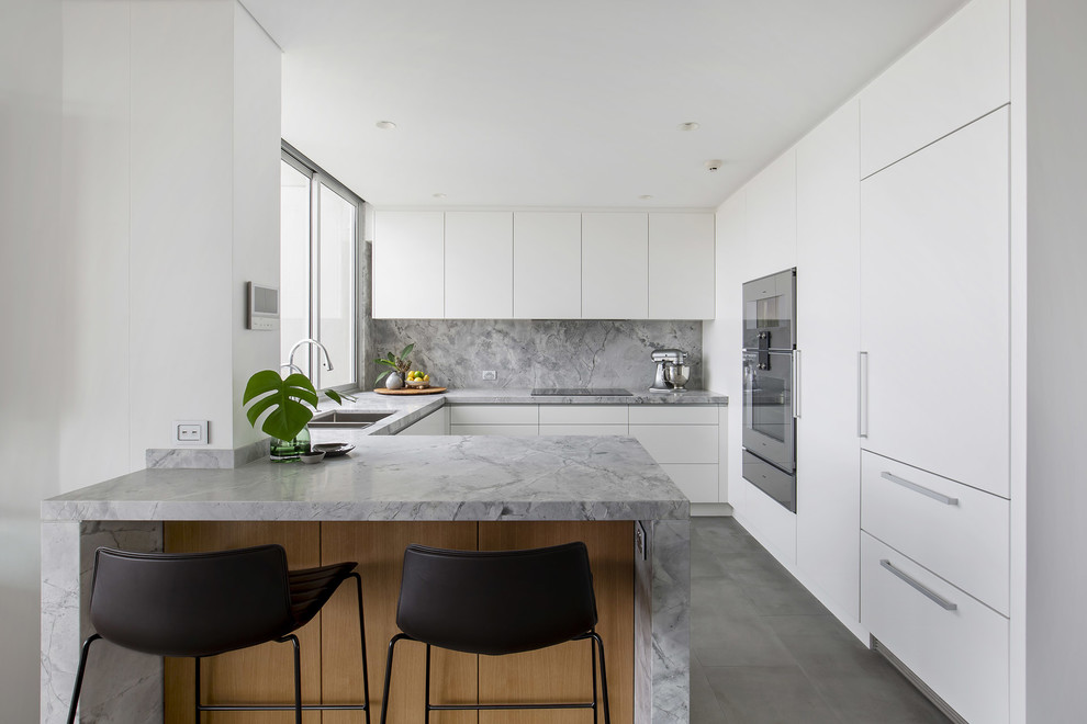 Idéer för att renovera ett avskilt, mellanstort funkis grå grått u-kök, med en undermonterad diskho, släta luckor, vita skåp, granitbänkskiva, grått stänkskydd, stänkskydd i sten, rostfria vitvaror, klinkergolv i keramik, en halv köksö och grått golv