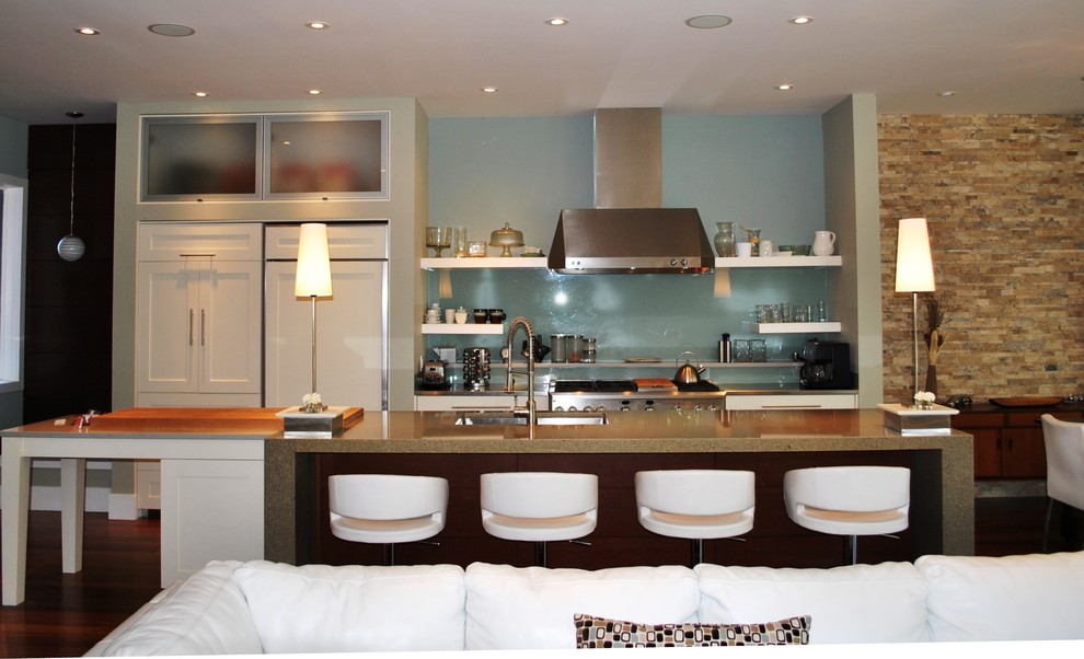 Modelo de cocina actual abierta con fregadero bajoencimera, armarios abiertos, puertas de armario blancas, salpicadero azul, salpicadero de vidrio templado y barras de cocina