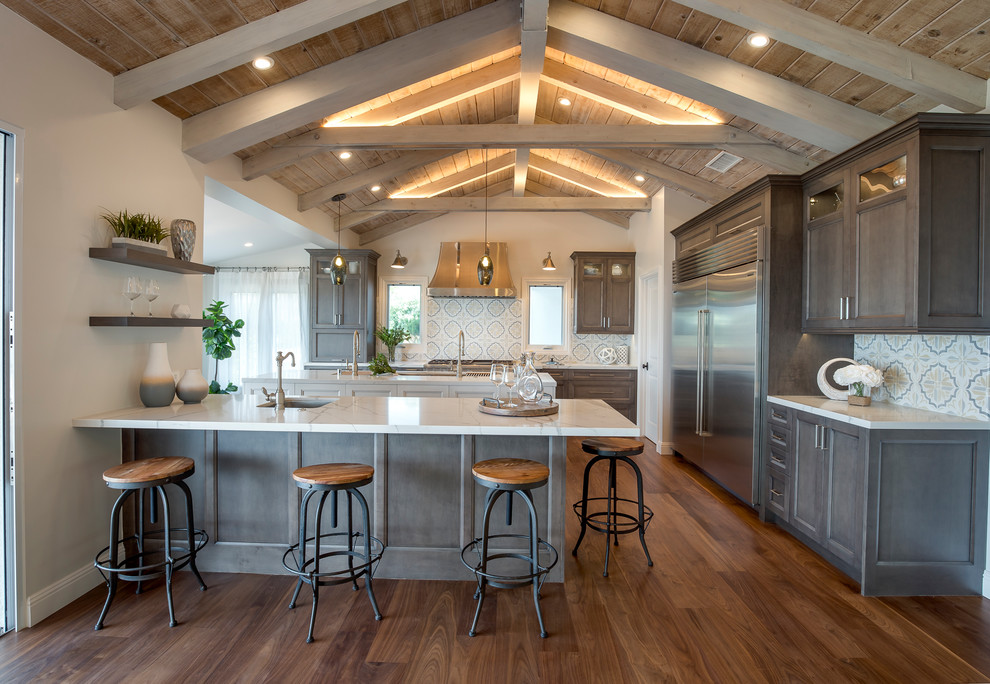 Large farmhouse u-shaped medium tone wood floor and brown floor open concept kitchen photo in Los Angeles with an undermount sink, recessed-panel cabinets, dark wood cabinets, quartzite countertops, multicolored backsplash, cement tile backsplash, stainless steel appliances and an island