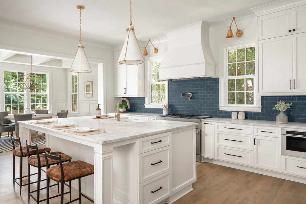 Idéer för ett stort klassiskt vit kök, med en rustik diskho, marmorbänkskiva, blått stänkskydd, stänkskydd i tunnelbanekakel, rostfria vitvaror, mellanmörkt trägolv och en köksö