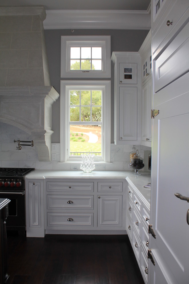 Foto de cocinas en U tradicional cerrado con armarios con rebordes decorativos, puertas de armario blancas y una isla
