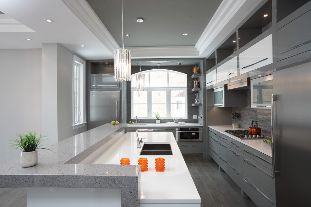 Inspiration for a large modern l-shaped kitchen remodel in Toronto with a double-bowl sink, flat-panel cabinets, gray cabinets, quartzite countertops, gray backsplash, matchstick tile backsplash, stainless steel appliances and a peninsula
