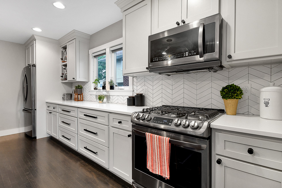 Klassisk inredning av ett mellanstort vit linjärt vitt kök med öppen planlösning, med en undermonterad diskho, skåp i shakerstil, grå skåp, bänkskiva i kvarts, vitt stänkskydd, stänkskydd i keramik, rostfria vitvaror, mörkt trägolv, en köksö och svart golv