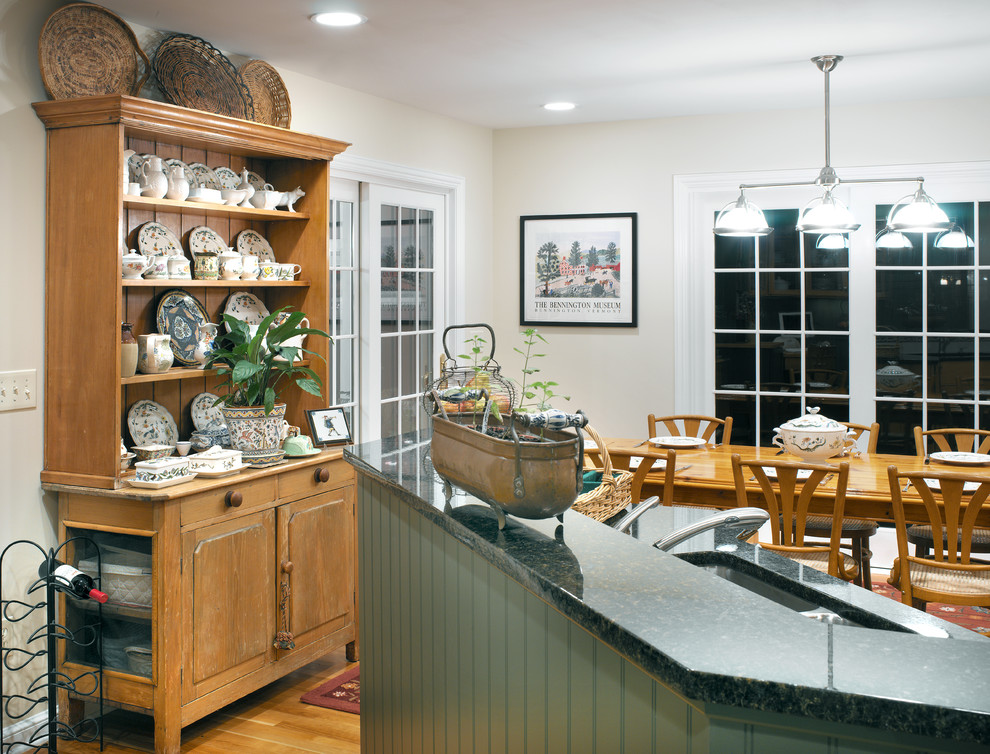 Klassisk inredning av ett kök, med en undermonterad diskho, skåp i shakerstil, granitbänkskiva, flerfärgad stänkskydd, stänkskydd i keramik, rostfria vitvaror, mellanmörkt trägolv och en halv köksö
