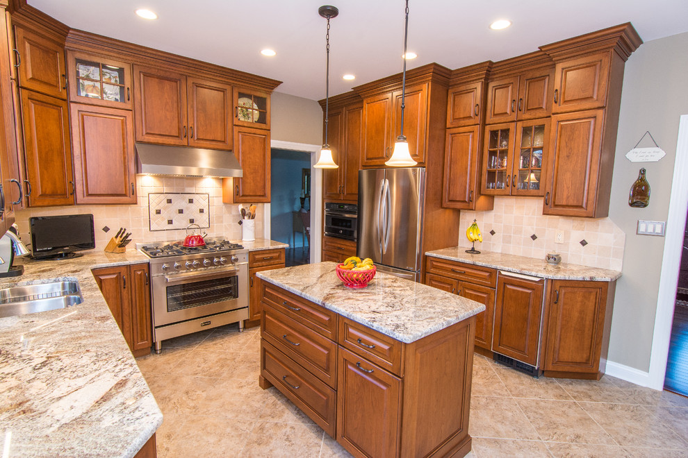 Example of a large classic u-shaped ceramic tile and beige floor enclosed kitchen design in Philadelphia with a double-bowl sink, raised-panel cabinets, brown cabinets, granite countertops, beige backsplash, stone tile backsplash, stainless steel appliances and an island