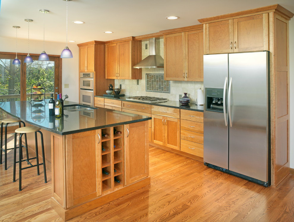 Trendy u-shaped medium tone wood floor eat-in kitchen photo in Columbus with an undermount sink, recessed-panel cabinets, medium tone wood cabinets, granite countertops, beige backsplash, stainless steel appliances and an island