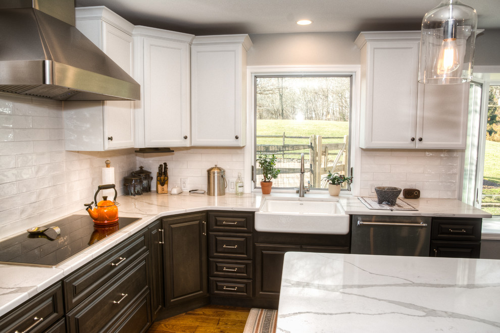 Klassisk inredning av ett stort vit vitt u-kök, med en rustik diskho, luckor med upphöjd panel, svarta skåp, bänkskiva i kvarts, vitt stänkskydd, stänkskydd i keramik, rostfria vitvaror, mellanmörkt trägolv, en köksö och brunt golv