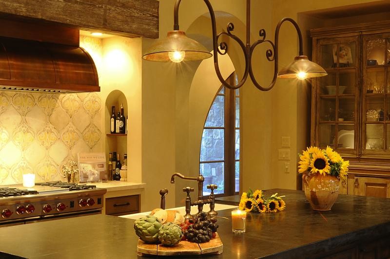 Offene, Mittelgroße Mediterrane Küche in L-Form mit hellbraunen Holzschränken, Küchengeräten aus Edelstahl, braunem Holzboden, Kücheninsel, Landhausspüle und Rückwand aus Zementfliesen in Sonstige