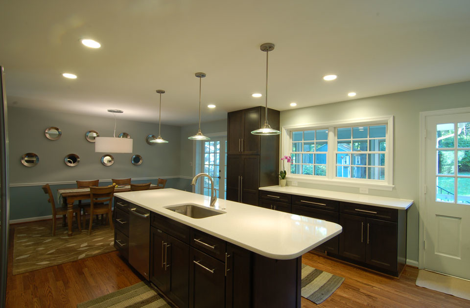 Inspiration for a mid-sized transitional galley medium tone wood floor eat-in kitchen remodel in DC Metro with an undermount sink, shaker cabinets, brown cabinets, quartz countertops, white backsplash, stainless steel appliances and an island