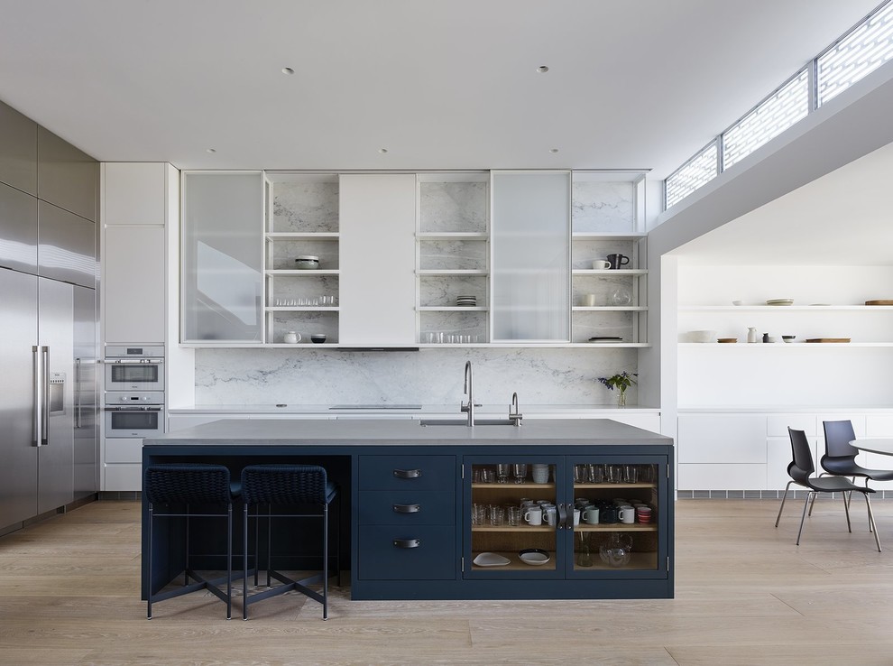 This is an example of a modern l-shaped kitchen/diner in Los Angeles with a submerged sink, flat-panel cabinets, white cabinets, stainless steel appliances, medium hardwood flooring, an island, brown floors and grey worktops.