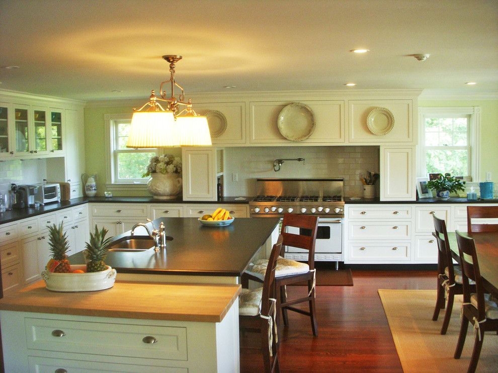 Example of a large classic l-shaped medium tone wood floor open concept kitchen design in Providence with a double-bowl sink, recessed-panel cabinets, white cabinets, white backsplash, stainless steel appliances and an island