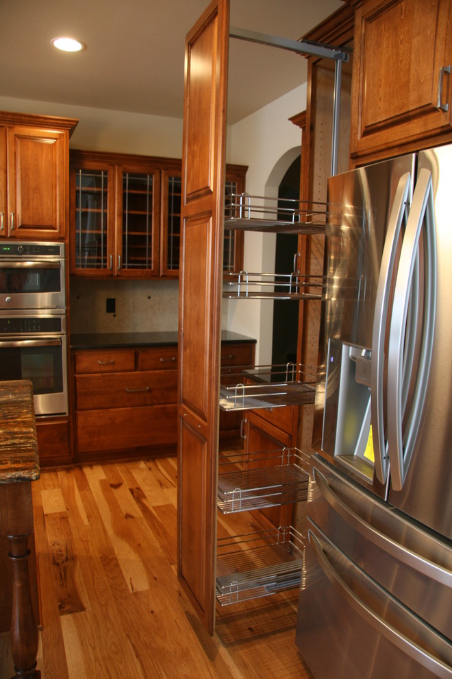 Mittelgroße Klassische Küche mit dunklen Holzschränken, Küchengeräten aus Edelstahl, braunem Holzboden, Kücheninsel und braunem Boden in Milwaukee