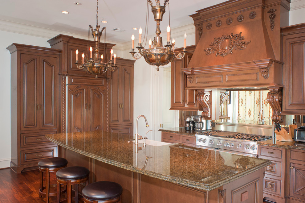 Example of a mid-sized classic single-wall medium tone wood floor eat-in kitchen design in Houston with a farmhouse sink, louvered cabinets, medium tone wood cabinets, granite countertops, paneled appliances and an island
