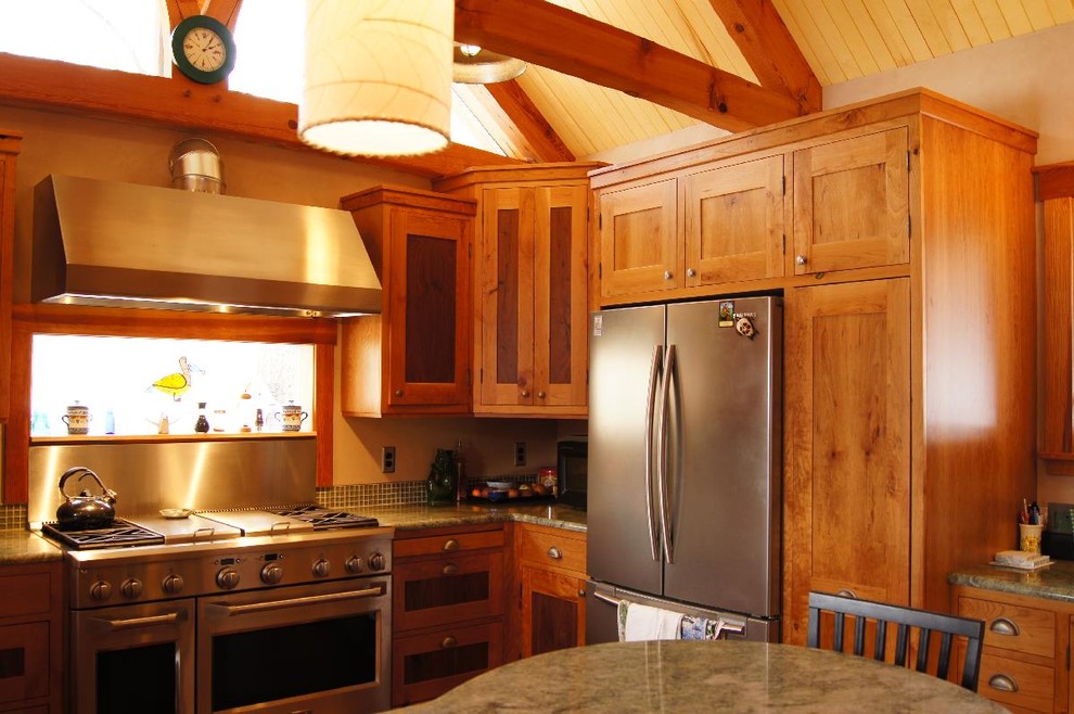 Inredning av ett klassiskt litet kök, med en undermonterad diskho, skåp i shakerstil, skåp i mellenmörkt trä, granitbänkskiva, grönt stänkskydd, stänkskydd i glaskakel, rostfria vitvaror, mellanmörkt trägolv och en halv köksö