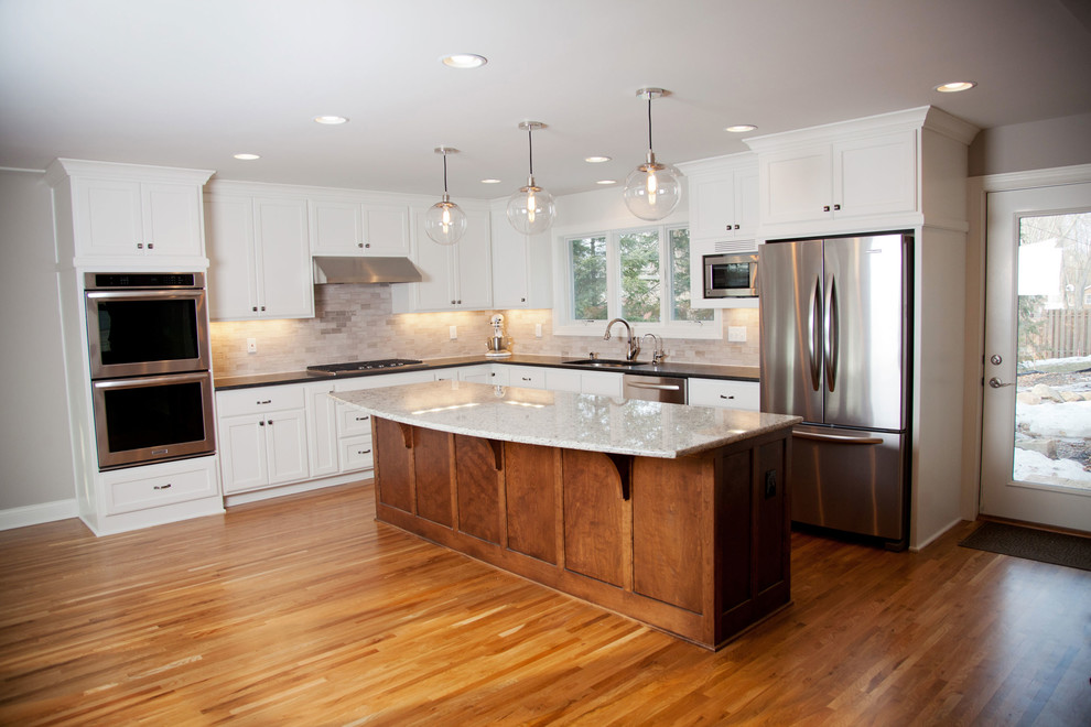 Bild på ett stort funkis kök, med skåp i shakerstil, vita skåp, granitbänkskiva, beige stänkskydd, stänkskydd i keramik, rostfria vitvaror, mellanmörkt trägolv, en köksö och en dubbel diskho