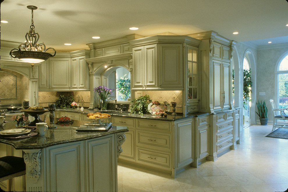 Inspiration for a huge timeless l-shaped travertine floor enclosed kitchen remodel in Philadelphia with an undermount sink, raised-panel cabinets, white cabinets, granite countertops, beige backsplash, stone tile backsplash, paneled appliances and an island