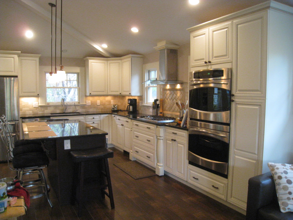 Exempel på ett mellanstort klassiskt kök, med en undermonterad diskho, luckor med upphöjd panel, vita skåp, bänkskiva i kvarts, beige stänkskydd, stänkskydd i stenkakel, rostfria vitvaror, mörkt trägolv och en köksö