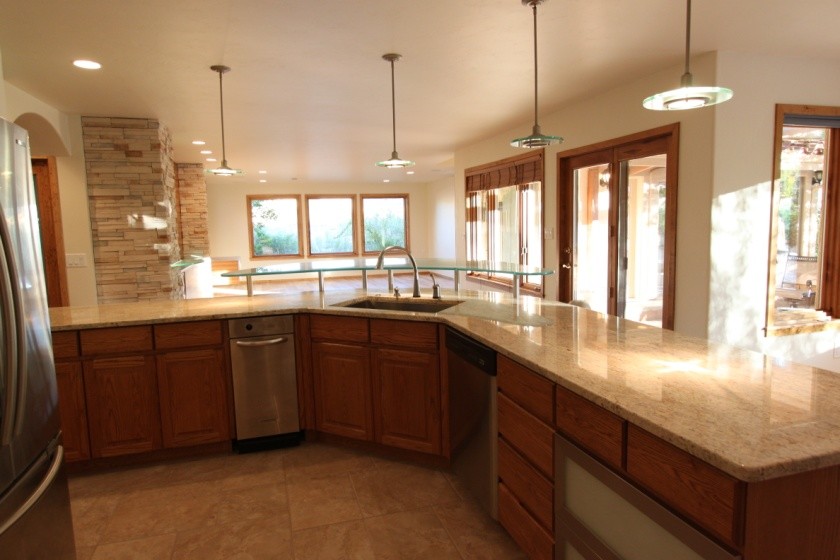 Foto på ett funkis kök, med en undermonterad diskho, luckor med glaspanel, skåp i rostfritt stål, bänkskiva i glas och rostfria vitvaror