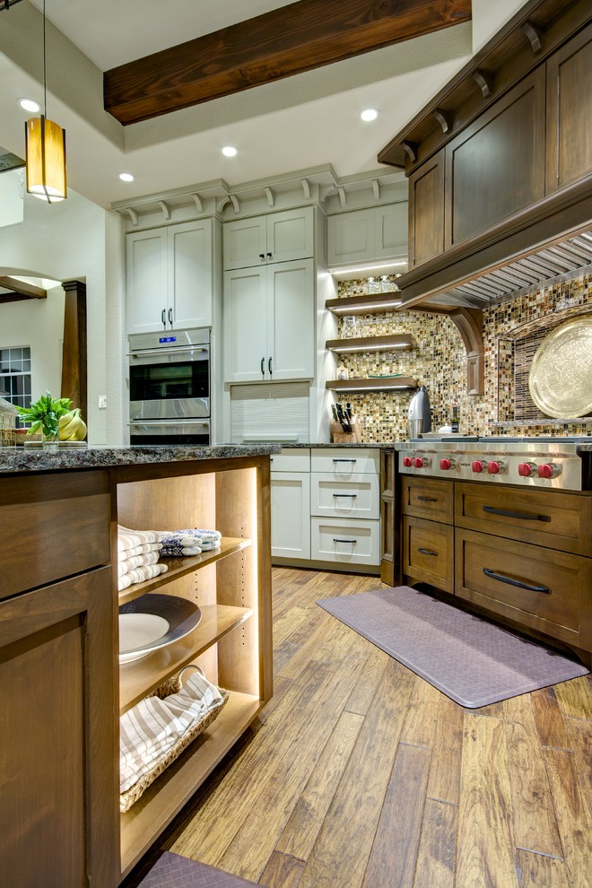 Inspiration for a large craftsman l-shaped medium tone wood floor eat-in kitchen remodel in Austin with shaker cabinets, medium tone wood cabinets, granite countertops, multicolored backsplash, mosaic tile backsplash, stainless steel appliances and an island