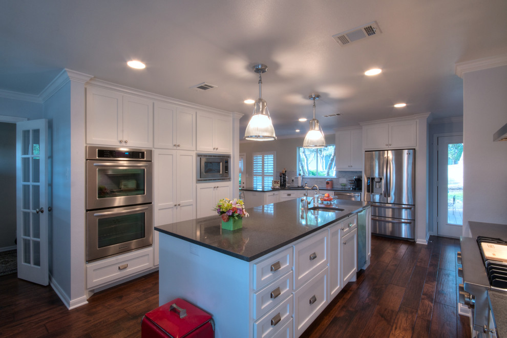 Large contemporary u-shaped kitchen/diner in Austin with a submerged sink, shaker cabinets, white cabinets, engineered stone countertops, white splashback, stainless steel appliances, medium hardwood flooring and an island.