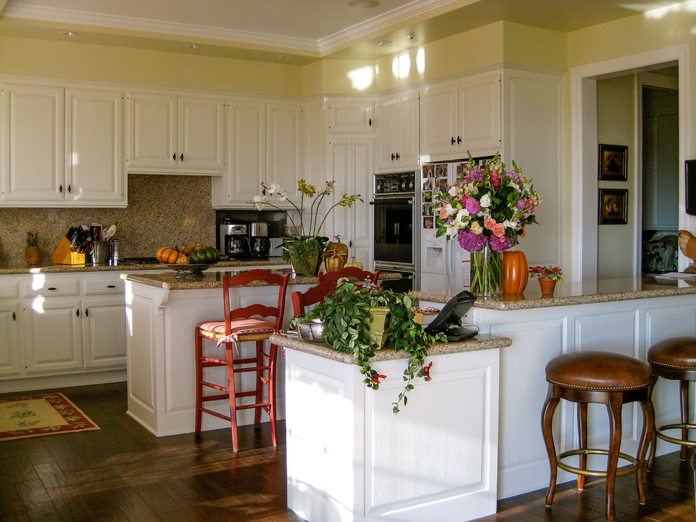 На фото: п-образная кухня-гостиная среднего размера в классическом стиле с фасадами с выступающей филенкой, коричневыми фасадами, деревянной столешницей и островом с