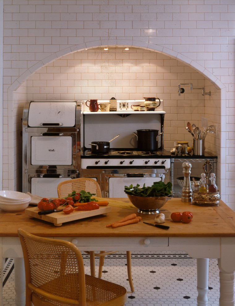 Стильный дизайн: кухня в стиле фьюжн с белым фартуком, фартуком из плитки кабанчик, островом и белой техникой - последний тренд