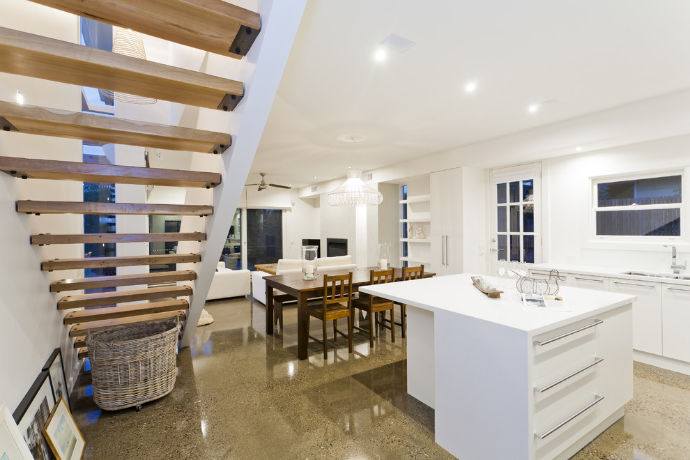 This is an example of a contemporary open plan kitchen in Melbourne with flat-panel cabinets and white cabinets.