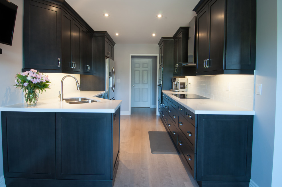 Inspiration for a small modern galley enclosed kitchen in Toronto with a double-bowl sink, shaker cabinets, dark wood cabinets, white splashback, metro tiled splashback, stainless steel appliances, dark hardwood flooring, no island and marble worktops.