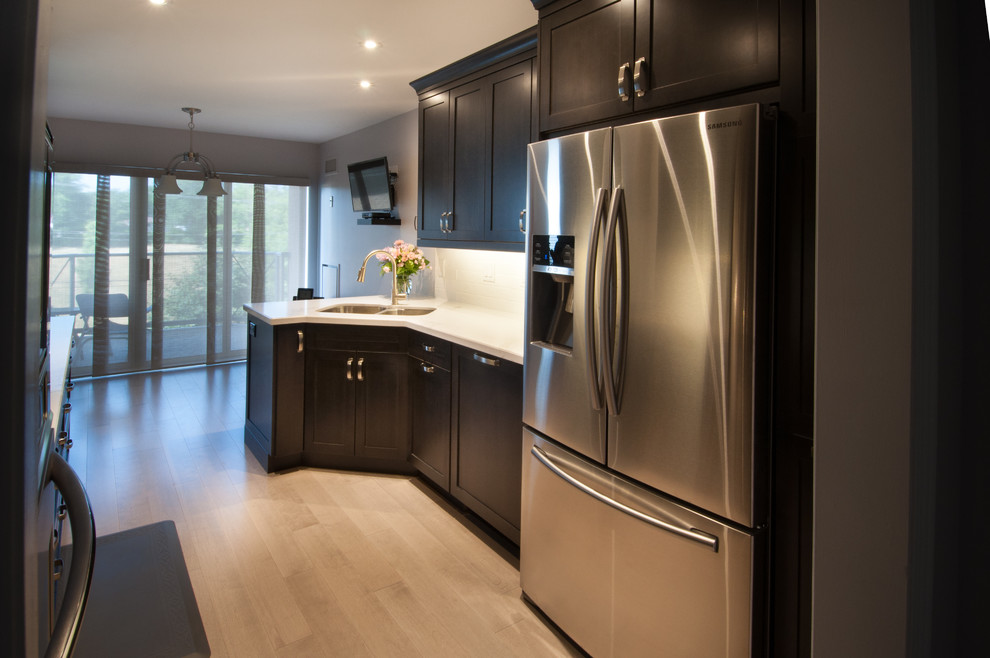 Design ideas for a small modern galley kitchen/diner in Toronto with a double-bowl sink, shaker cabinets, dark wood cabinets, white splashback, metro tiled splashback, stainless steel appliances, dark hardwood flooring, no island and marble worktops.