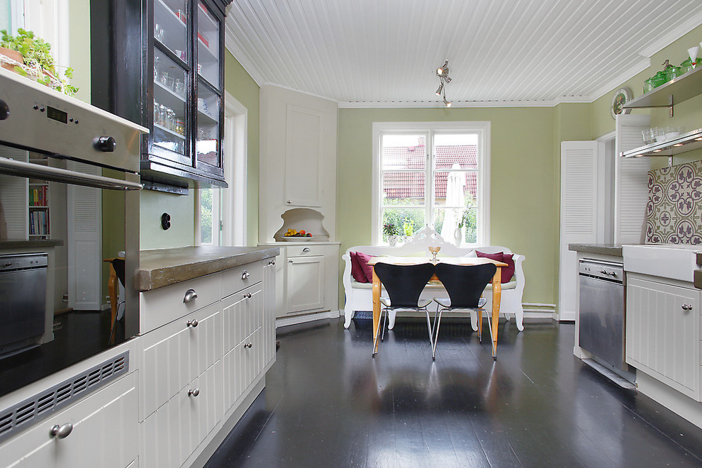 Eklektisk inredning av ett mellanstort kök, med luckor med upphöjd panel, vita skåp, träbänkskiva, rostfria vitvaror och målat trägolv