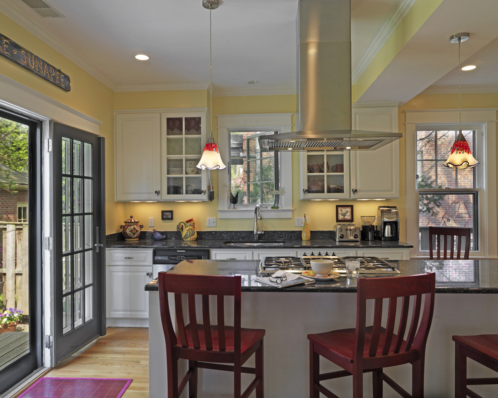 Klassisk inredning av ett kök, med luckor med upphöjd panel, vita skåp och svart stänkskydd